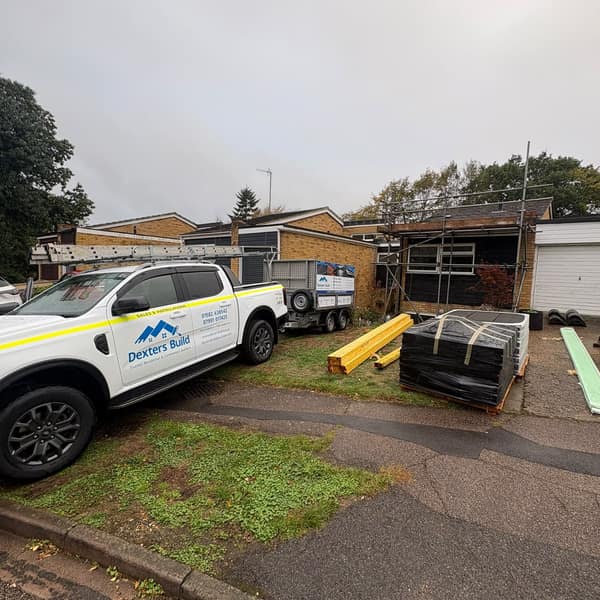 The Dexters Build pickup on the drive next to pallets of new tiles and battens