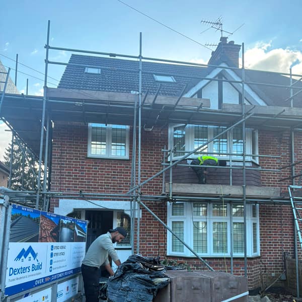 Unwrapping a pallet of new roof tiles next to the Dexters Build trailer