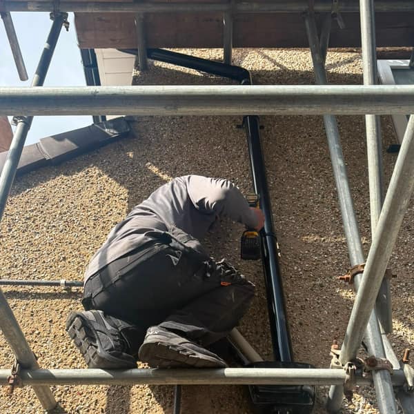 Fitting a downpipe from the scaffold